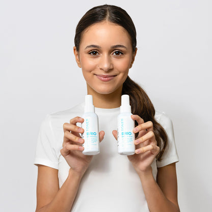 Young woman is holding two Skin Renew Toner bottles, smiling and looking directly to camera with opened eyes. Skin Renew Toner is dermatologically and clinically tested.